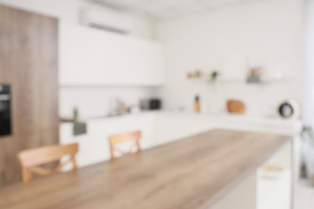 Blurred view of light kitchen with white counters and tableの写真素材