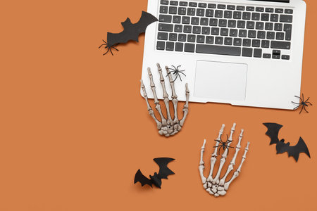 Modern laptop and decor for Halloween on orange backgroundの写真素材