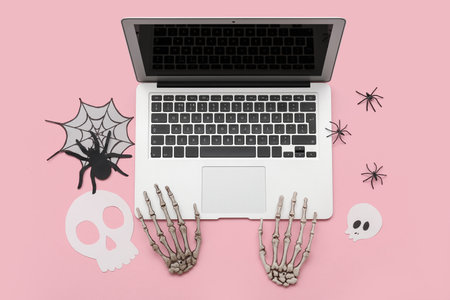 Composition with modern laptop and decor for Halloween on pink backgroundの写真素材