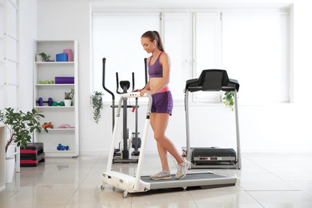 Sporty young woman training on treadmill in gym