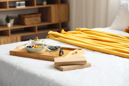 Tray with tasty breakfast and books on bed in room, closeup