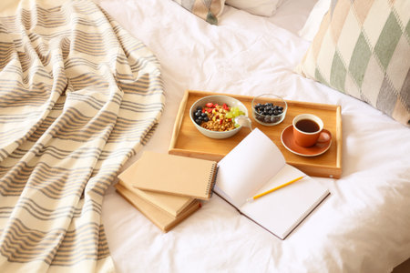 Tray with breakfast and books on bed, closeup