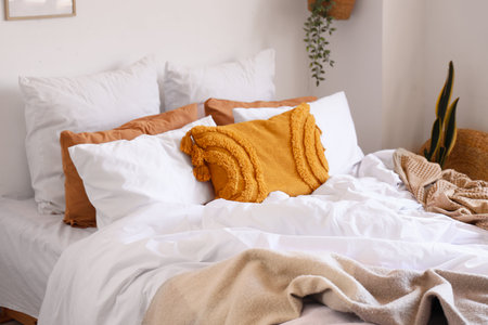 Big comfortable bed with crumpled linen in bedroomの写真素材