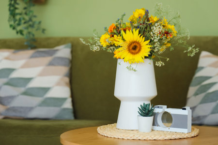 Wild flowers in vase, succulent and toy camera on coffee table in living room. Closeupの写真素材