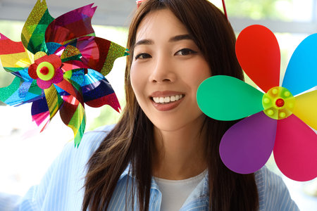 Young Asian woman with toy windmills at home, closeup