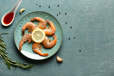Plate with tasty boiled shrimps, rosemary and lemon on green backgroundの写真素材