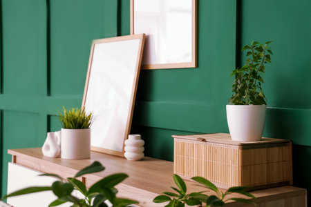 Dresser with photo frames, vases and houseplants near green wallの写真素材