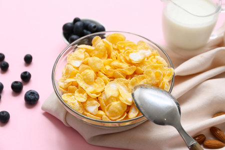 Napkin, berries, bowl with cornflakes and milk on pink background, closeupの写真素材