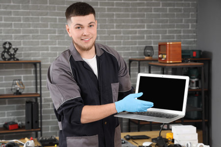 Male technician with repaired laptop in service centerの写真素材