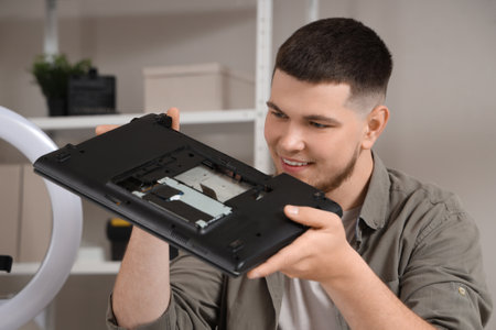 Male technician repairing laptop at table in service center, closeupの写真素材
