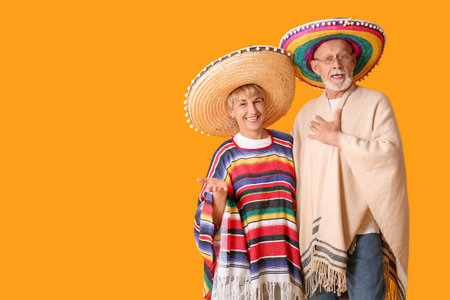 Mature couple in sombrero hats on yellow backgroundの写真素材