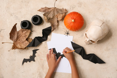 Child with supplies making Halloween decorations on grunge beige backgroundの写真素材