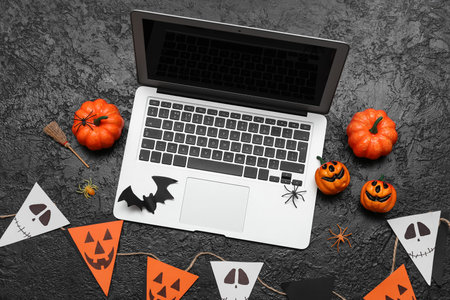 Composition with modern laptop and decor for Halloween celebration on dark backgroundの写真素材