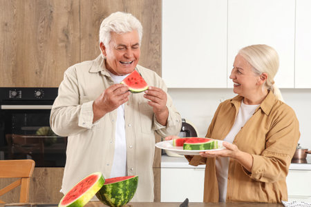 Mature couple with cut watermelon in kitchenの写真素材