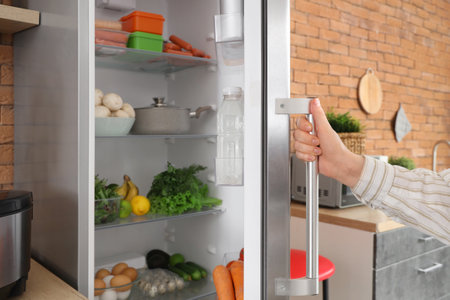 Woman closing refrigerator in kitchen. Closeupの写真素材
