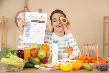 Young woman with meal plan and avocado in kitchen. Diet concept