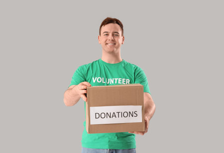 Male volunteer with donation box on light backgroundの写真素材