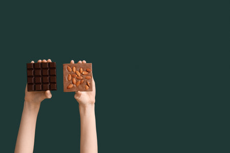 Female hands with different sweet chocolate bars on green backgroundの写真素材