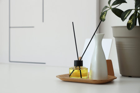 Aroma diffuser and vase in wooden tray on table in room, closeup