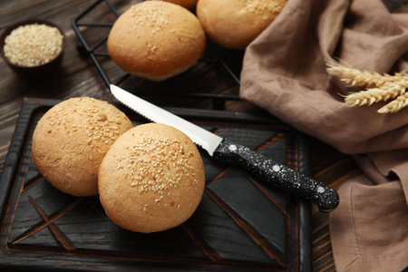 Stand and board of fresh buns with sesame seeds on wooden backgroundの写真素材