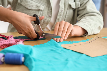 Female tailor cutting cloth at table in atelier, closeupの写真素材