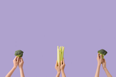 Hands with fresh broccoli and celery on lilac backgroundの写真素材