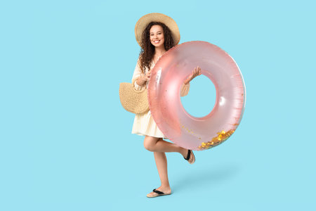 Beautiful young African-American woman with inflatable ring on blue background