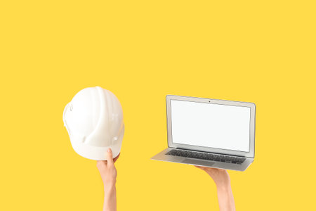 Architects with hardhat and blank laptop on yellow backgroundの写真素材