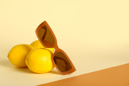 Stylish brown sunglasses and fresh lemons on colorful backgroundの写真素材