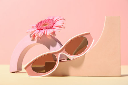 Decorative podiums with stylish sunglasses and gerbera flower on colorful backgroundの写真素材