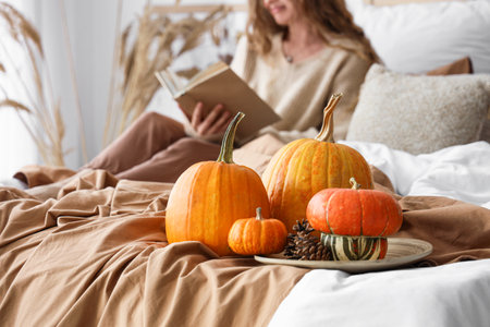 Pumpkins on bed of woman reading book at home, closeupの写真素材