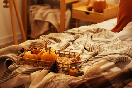 Wicker tray with autumn decorations on bed in bedroom at eveningの写真素材