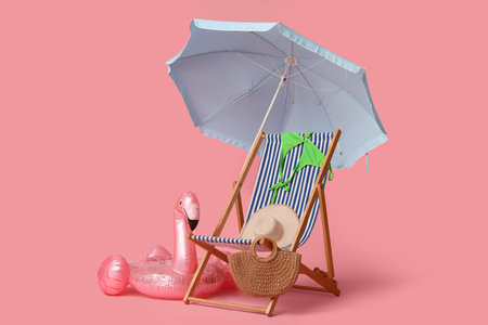 Deck chair, beach umbrella, hat, wicker bag, swimsuit and inflatable ring on pink backgroundの写真素材