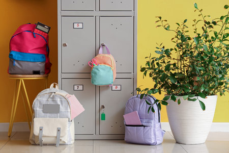 Locker with school backpacks near yellow wall