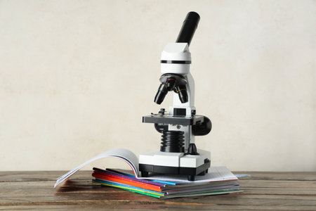 Modern microscope with and copybooks on wooden table against white grunge backgroundの写真素材