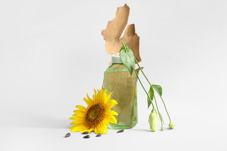 Composition with bottle of cosmetic product, sunflower and tree bark on light backgroundの写真素材