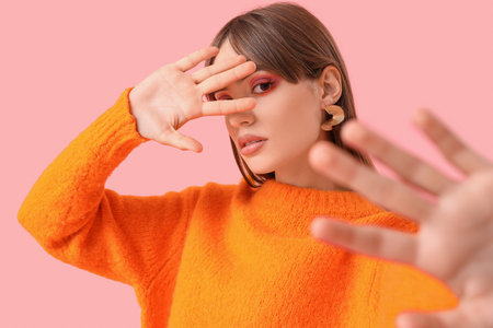 Beautiful young fashionable woman in stylish outfit posing on pink backgroundの写真素材