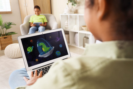 Cute happy African-American children watching cartoons on tablet and laptop at home