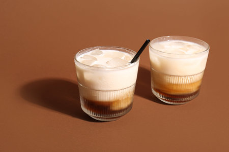 Glasses of White Russian cocktail on brown background