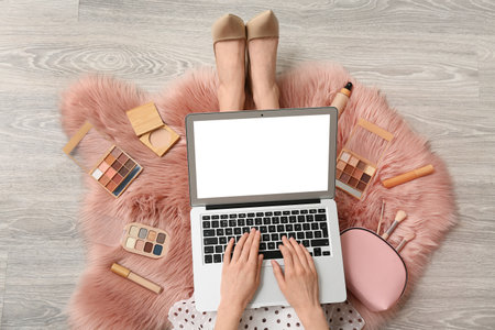 Makeup artist with cosmetic products using laptop on carpet, top viewの写真素材