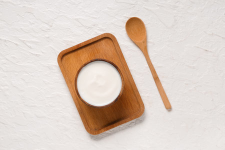 Wooden bowl of tasty yogurt on white background