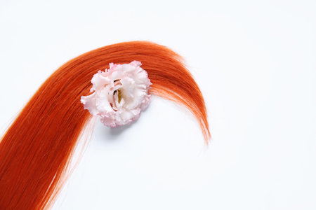 Red hair strand and flower on white background, closeupの写真素材