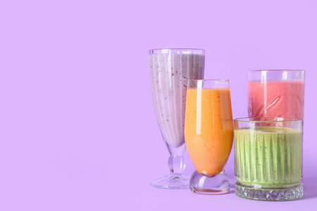 Glasses of different fresh smoothie on lilac backgroundの写真素材