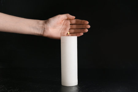 Hand with burning candle on black background. Day of Remembranceの写真素材