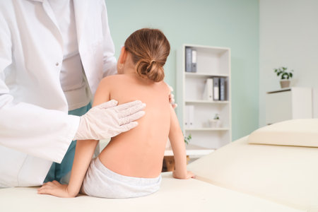 Female osteopath working with little patient on couch in clinic, back viewの写真素材