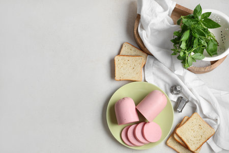 Plate with slices of tasty boiled sausage, bread and basil on grunge white backgroundの写真素材