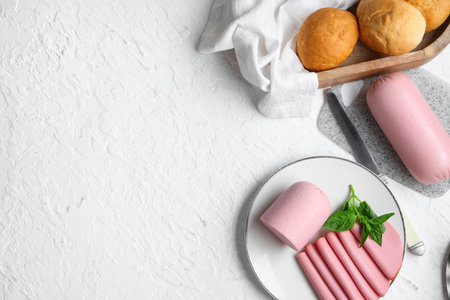 Plate with slices of tasty boiled sausage, bread and basil on grunge white backgroundの写真素材