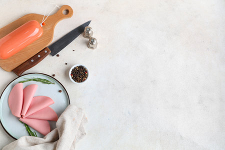 Plate with slices of tasty boiled sausage, rosemary and peppercorns on grunge white backgroundの写真素材