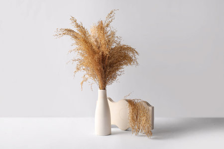 Vase with dry reeds and plaster decor on white background