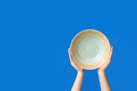 Hands holding empty plate on blue backgroundの写真素材